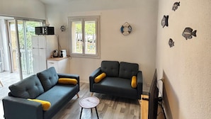 Un salón amplio con dos sofás oscuros, una mesita redonda y un televisor.