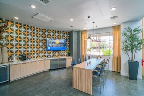 Une cuisine moderne dotée d’un îlot central, d’un téléviseur à écran plat fixé au mur et d’une grande fenêtre offrant une vue sur l’extérieur.