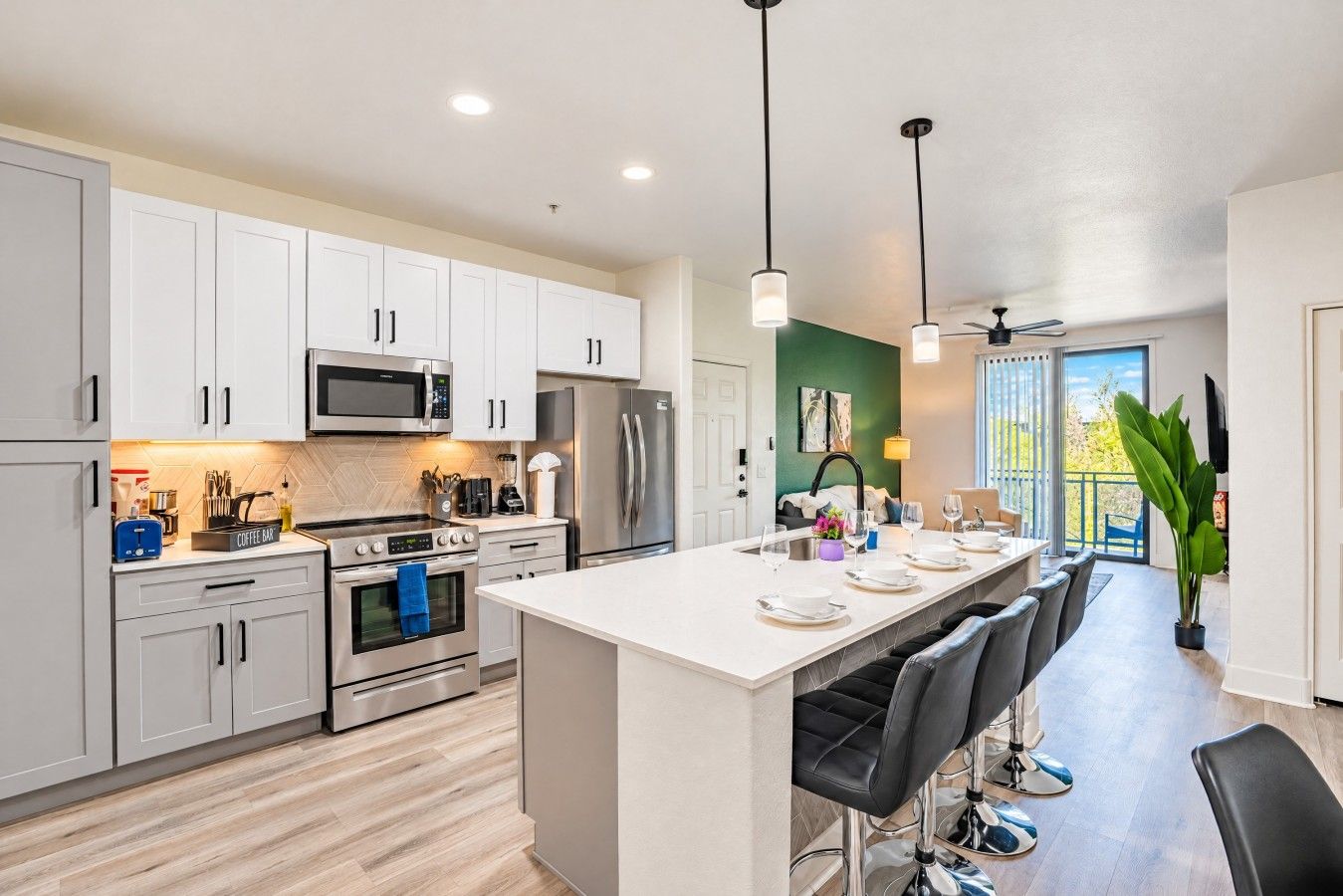 A modern kitchen with white cabinetry, stainless steel appliances, and a central island with bar stools.