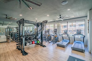 Une salle de sport équipée de machines d’exercice, de tapis de course et dotée d’un mur recouvert de miroirs.