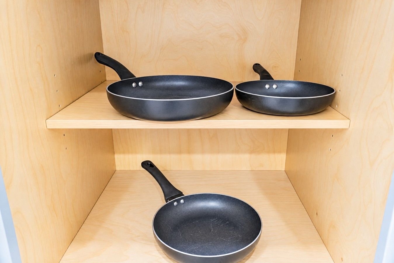 Trois poêles noires sur des étagères en bois.