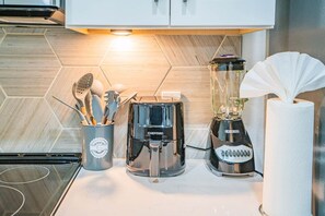 Un plan de travail de cuisine avec une machine à café, un mixeur et un porte-ustensiles.