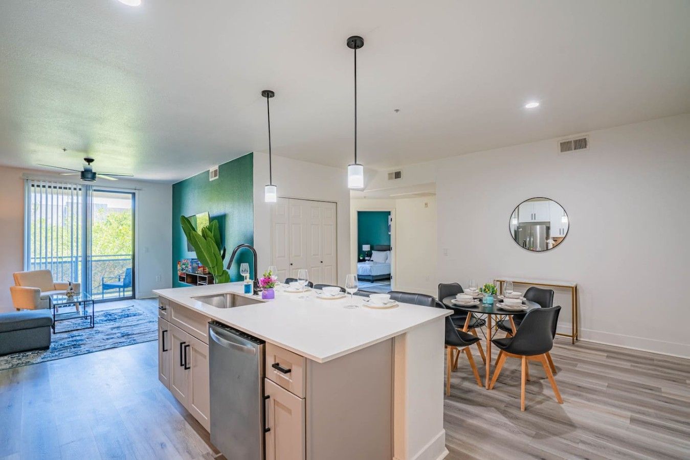 Une cuisine moderne avec un îlot central, un coin repas avec des chaises et une vue sur une chambre.