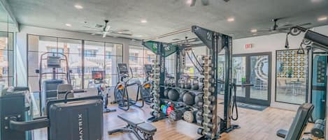 Un gimnasio con equipamiento de ejercicio, un ventilador de techo y vistas al exterior.