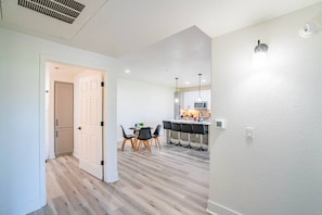Une cuisine moderne avec un coin repas, un plancher en bois et une porte blanche donnant sur une autre pièce.