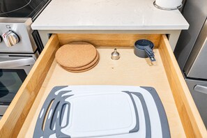 A kitchen drawer with a cutting board, cork pads, and a metal utensil. - Near Westgate Entertainment District | Pool, Gym, (Glendale)