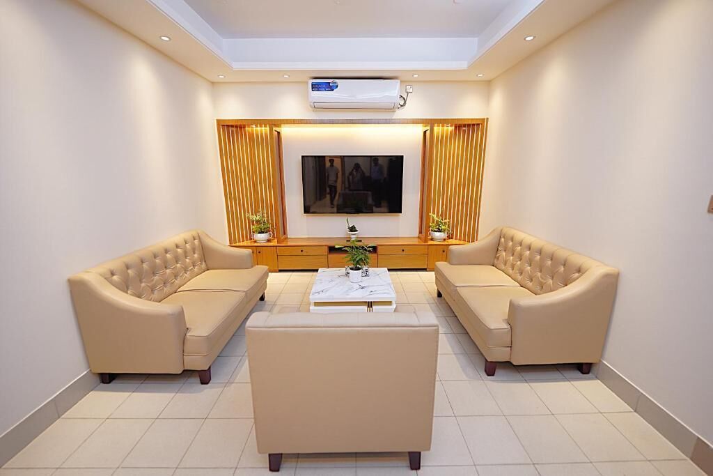 Una sala de estar moderna con dos sofás beige, una mesa de centro y un televisor de pantalla plana montado en la pared.