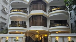 A modern multi-story building with a central entrance, balconies on each floor, and a motorcycle parked in front. - Tourister Bd Ltd (Dhaka)