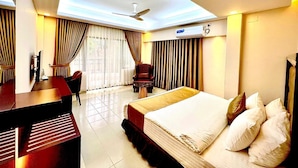 A hotel room with a bed, desk, chair, and a ceiling fan. - Tourister Bd Ltd (Dhaka)