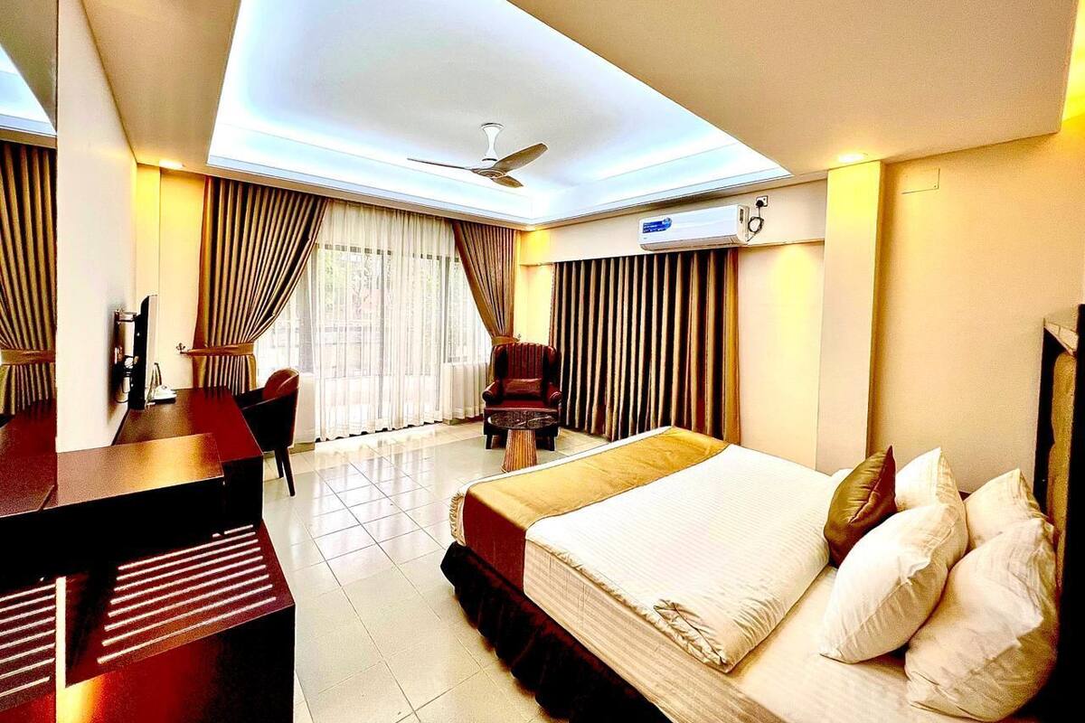A hotel room with a bed, desk, chair, and a ceiling fan.