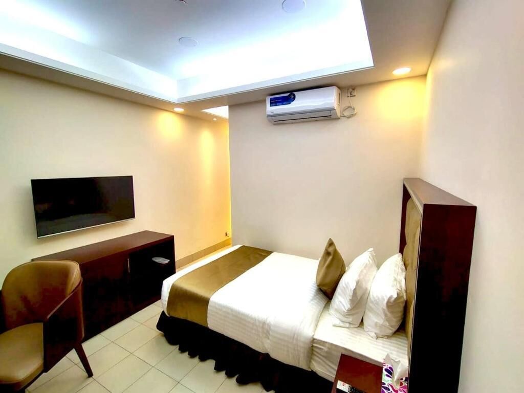 Une chambre d’hôtel équipée d’un lit, d’une télévision, d’un bureau et d’un appareil de climatisation.