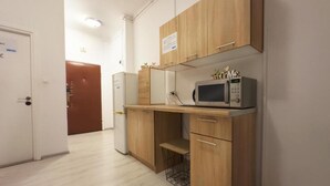 A compact kitchen with wooden cabinets, a microwave, and a small countertop. - Fantastic Inn Warsaw - NS54 (Warsaw)