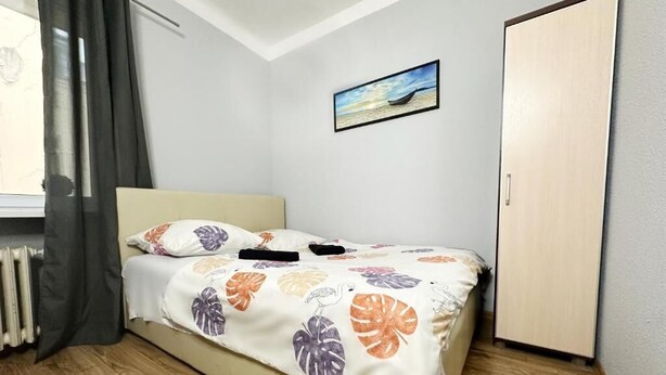 A bedroom with a bed, a radiator, a window with curtains, a painting on the wall, and a door. - Fantastic Inn Warsaw - NS54 (Warsaw)