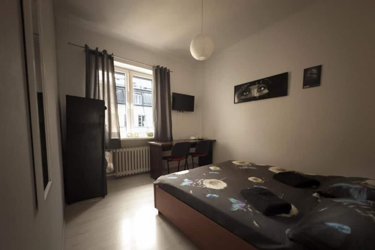 A bedroom with a bed, a desk, and a chair.