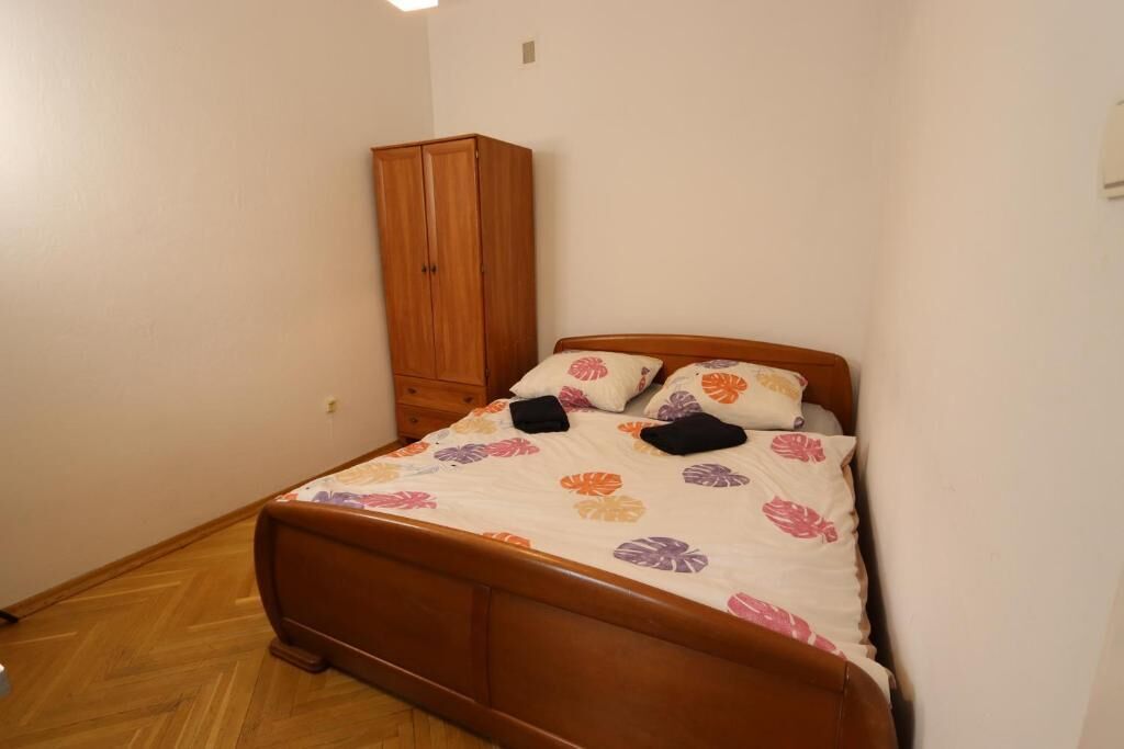 A small bedroom with a wooden bed, a wardrobe, and a floral bedspread.