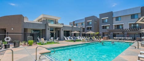 A swimming pool area with lounge chairs and a poolside deck.
