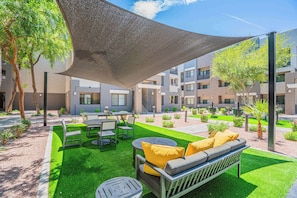 Une terrasse extérieure avec une table, des chaises et un canapé, le tout installé sous un auvent.