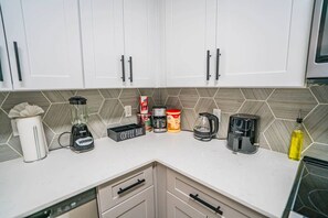 A kitchen with white cabinets, a coffee bar area, a blender, a coffee maker, a toaster, and a bottle of oil. - Chic Stay Near Westgate | Pool, Gym, Parking & W/D (Glendale)