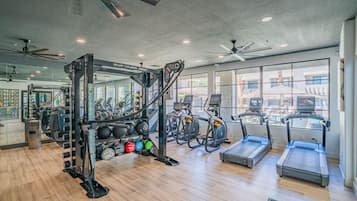 Une salle de sport équipée de matériel d’exercice, de tapis de course et de stations d’entraînement avec des poids.