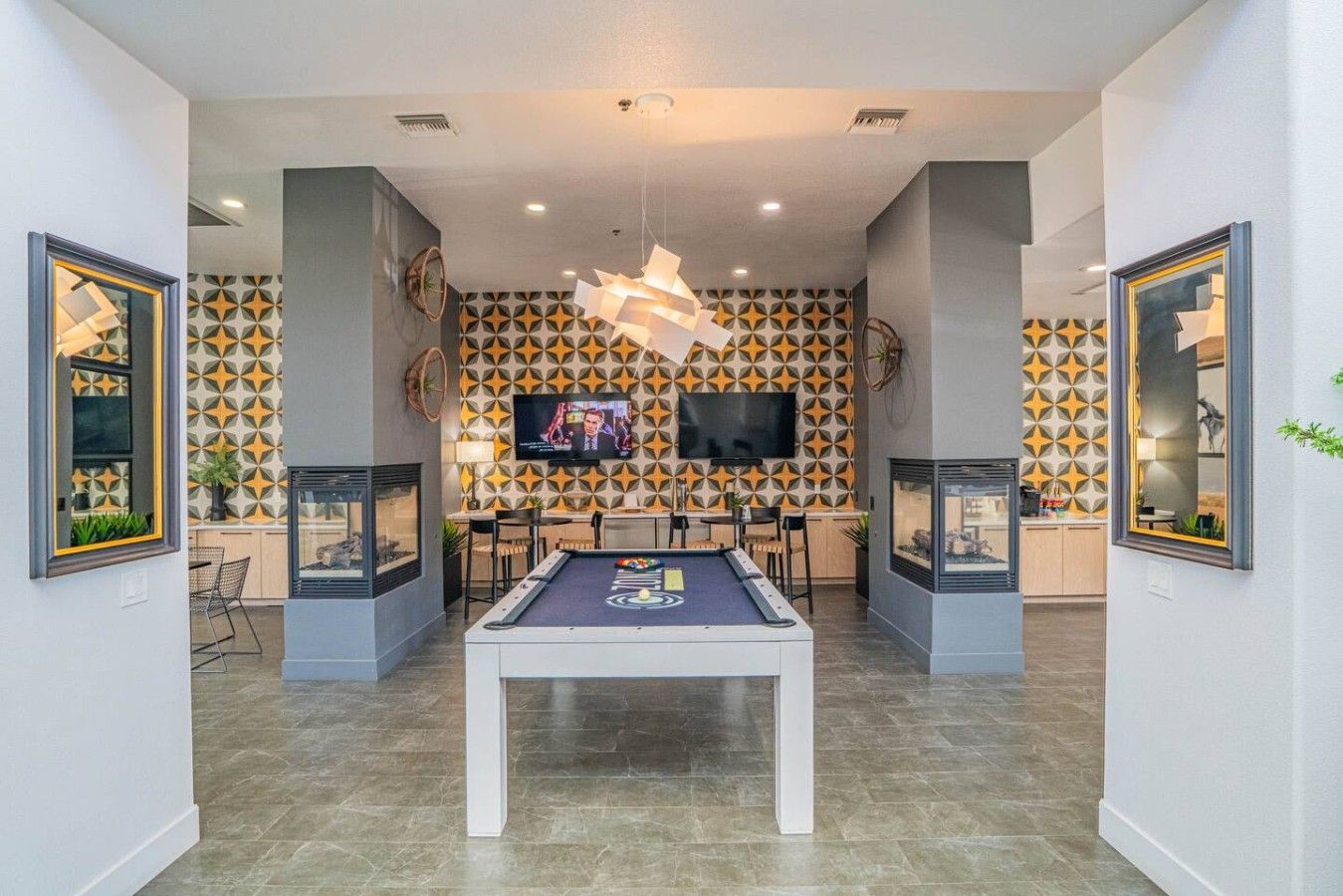 Un espace intérieur moderne doté d’une table de billard, d’un coin salon et de motifs décoratifs sur les murs.
