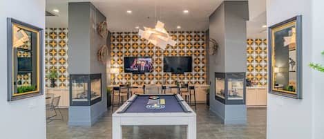 Un espace intérieur moderne doté d’une table de billard, d’un coin salon et de motifs décoratifs sur les murs.