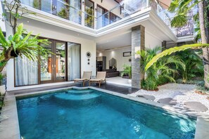 Ein modernes Haus mit Swimmingpool, Sitzgelegenheit im Freien und üppiger Bepflanzung.