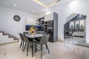 Eine moderne Küche mit Marmorarbeitsplatte, integriertem Backofen und Kühlschrank. Es gibt eine Essecke mit Tisch und Stühlen sowie eine Treppe zu einer anderen Ebene.