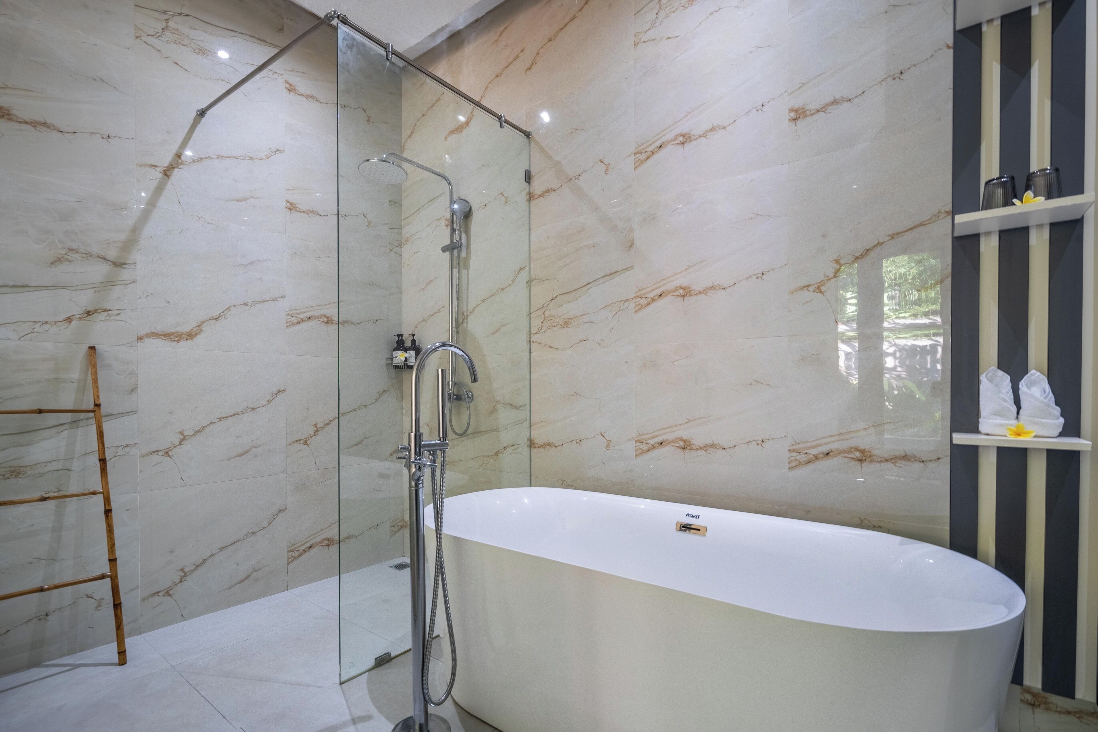 A modern bathroom with a freestanding bathtub, a glass-enclosed shower, and marble walls.