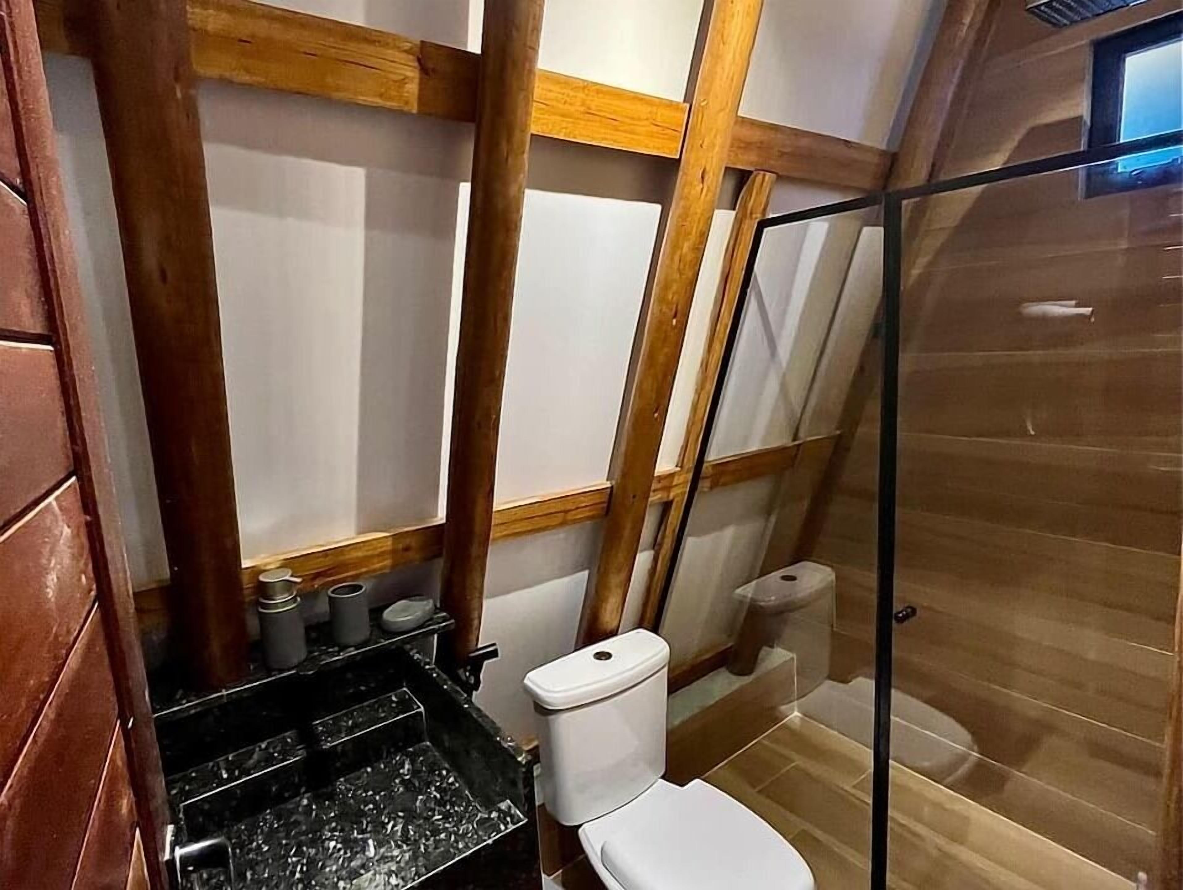 A small bathroom with a toilet, a shower enclosure, and a sink with a black countertop.