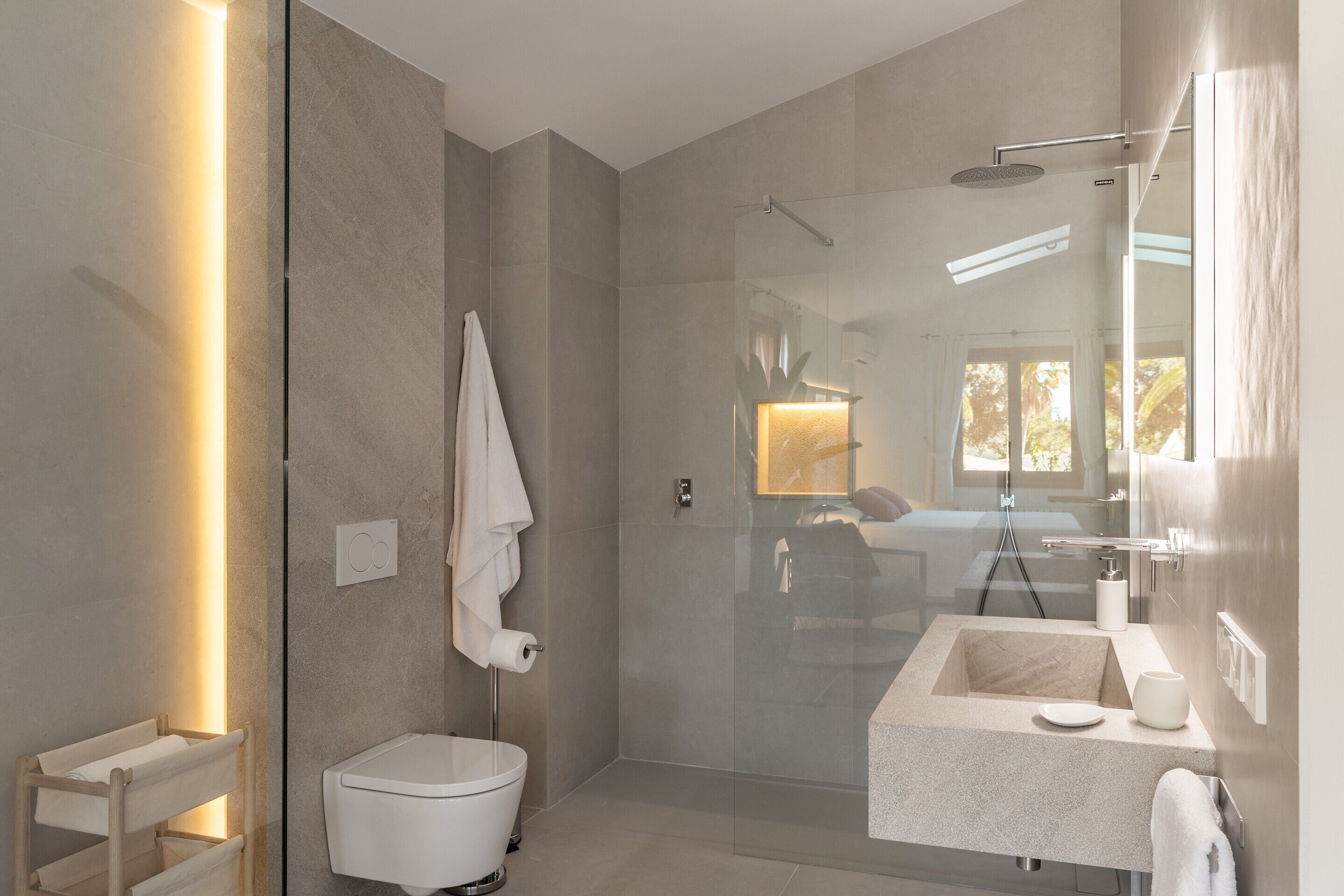 Une salle de bain moderne avec une douche à parois de verre, des toilettes blanches et un lavabo en marbre.