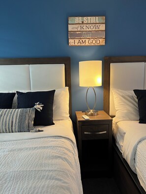 A hotel room with two beds, a nightstand with a lamp, and a motivational sign on the wall. - Christian Retreat Conference Center  (Bradenton)