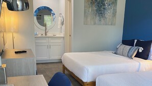 Una habitación de hotel con escritorio, dos camas, un espejo y una pared decorada en azul.