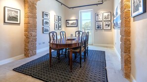 A dining area with a round table, chairs, a rug, and framed pictures on the walls.