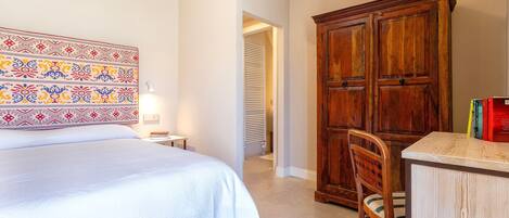 A bedroom with a bed, a wooden cabinet, a chair, and a patterned headboard.