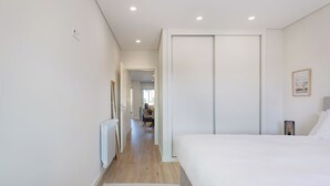 A modern hotel room with a large bed, a radiator, a desk, and a chair in the background. - The Pine Flat with Pool at Furadouro (Ovar)