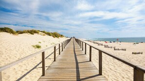 A wooden boardwalk leading to a beach with a clear sky. - The Pine Flat with Pool at Furadouro (Ovar)