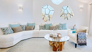 Een moderne woonkamer met een witte bank, decoratieve muurkunst en een glazen salontafel.