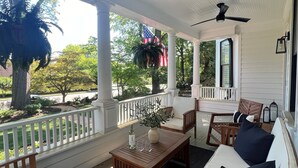 Een overdekte veranda met houten meubilair, een plafondventilator en een Amerikaanse vlag.