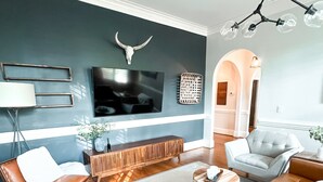 Een moderne woonkamer met een grote televisie, een leren bank en een opvallend decoratief wandobject.