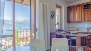 Una cocina con armarios de madera, una mesa de comedor con sillas, vista a montañas y un reloj en la pared.