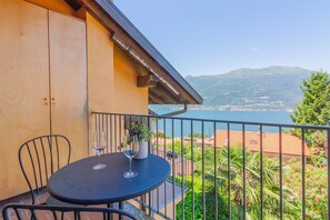 Un balcon avec une table et des chaises, donnant sur un plan d’eau et des montagnes.