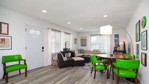 A modern living room with a sofa, chairs, a dining table, and a kitchen area. - Cozy Corner: Spacious Area & Outdoor Lounges! (Knoxville)