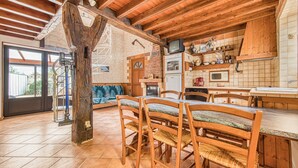 Eine rustikale Küche mit Holzbalken, einer Steinwand und einem gefliesten Boden.