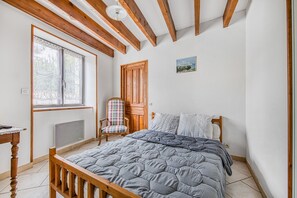 A bedroom with a wooden bed, a window, a chair, and a door.