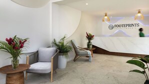 A modern reception area with a curved wall, a reception desk, and two lounge chairs. - Negril Footeprints Hotel (Negril)