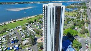 A high-rise hotel with a modern design, located near a marina with boats and a beach. - CASSA MQ - Oceanview 2BR Southport Gem for Family (Southport)