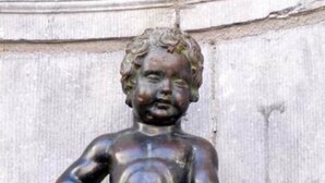 En bronzestatue af et barn med krøller, stående på en sokkel.