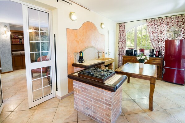 A kitchen with a brick stove, a dining table, and a refrigerator.