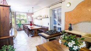 A dining area with a wooden table and chairs, a stove, and a potted plant. - VILLA LISA - COUNTRY HOUSE LISA. HOUSE WITH GARDEN 7 MINUTES WALK FROM THE SEA (Diano Marina)