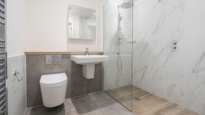 A modern bathroom with a toilet, sink, and glass-enclosed shower.
